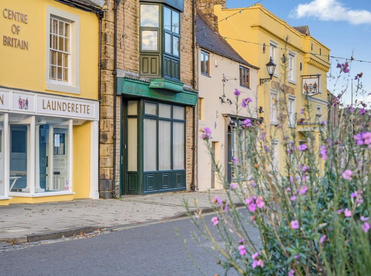 A street view with a yellow building labeled 'Centre of Britain' and a 'Laundryette' sign.