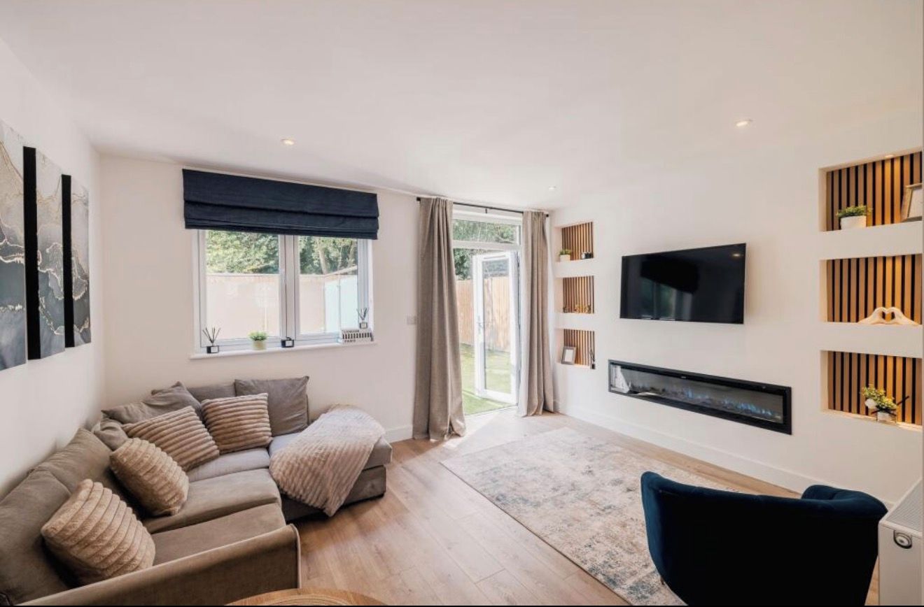 Un salon moderne avec un canapé, un téléviseur à écran plat et une cheminée.