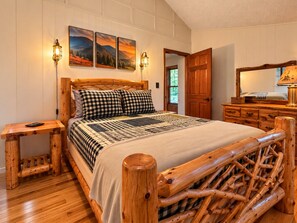 A wooden bed with a checkered bedspread, a bedside table, and a nightstand.