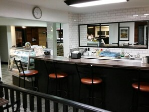 A bar area with stools, a counter, and a clock on the wall. - Wild Rose Country Inn (Grande Prairie)