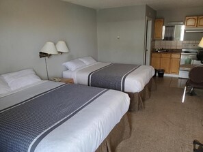 A hotel room with two beds, a kitchenette, and a bathroom. - Wild Rose Country Inn (Grande Prairie)