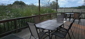 Eine Terrasse im Freien mit Tisch und Stühlen, umgeben von einem Holzdeck und einem Metallgeländer.