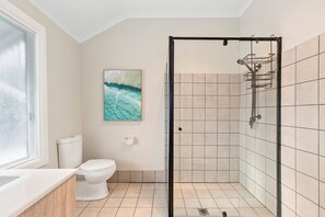 Une salle de bain avec une douche à parois de verre, des toilettes et un lavabo.