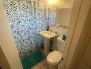 Une salle de bain équipée de toilettes, d’un lavabo et d’un rideau de douche à motifs géométriques.