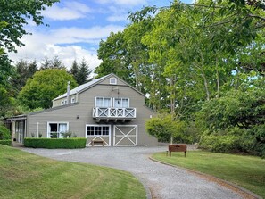 A two-story house with a front garage, a wooden bench, and a sign that reads 'The Barn.' - Boutique BarnStay/Games room,Boat parking on beautiful private grounds (Taupō)
