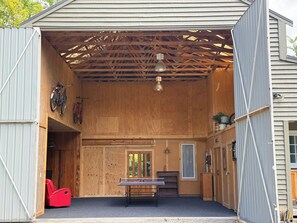 A covered outdoor area with a ping pong table, a bicycle, and a red chair. - Boutique BarnStay/Games room,Boat parking on beautiful private grounds (Taupō)