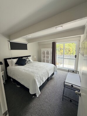 A bedroom with a bed, a desk, a window with curtains, and a view of the outside. - Boutique BarnStay/Games room,Boat parking on beautiful private grounds (Taupō)