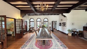 A spacious room with a long wooden table, a patterned rug, and a chandelier. - Glenhof Manor (Cape Town)