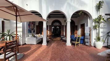 An outdoor patio with a herringbone floor, white columns, and seating areas.