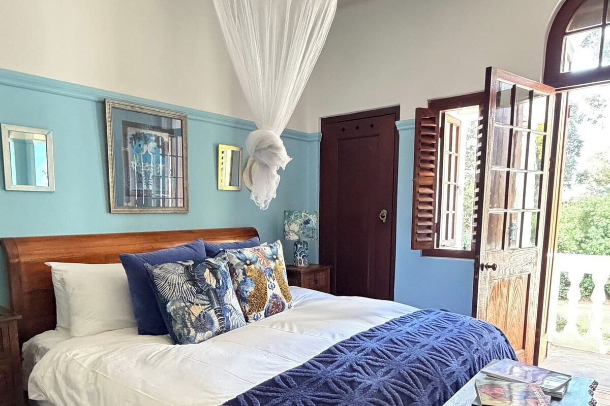 A bedroom with a bed, bedside table, and a window with shutters.