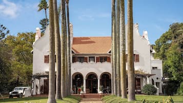A large, white building with a tiled roof, surrounded by tall palm trees.