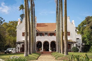 A large, white building with a tiled roof, surrounded by tall palm trees. - Glenhof Manor (Cape Town)