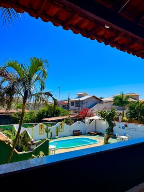A residential area with a swimming pool, palm trees, and houses with red-tiled roofs.