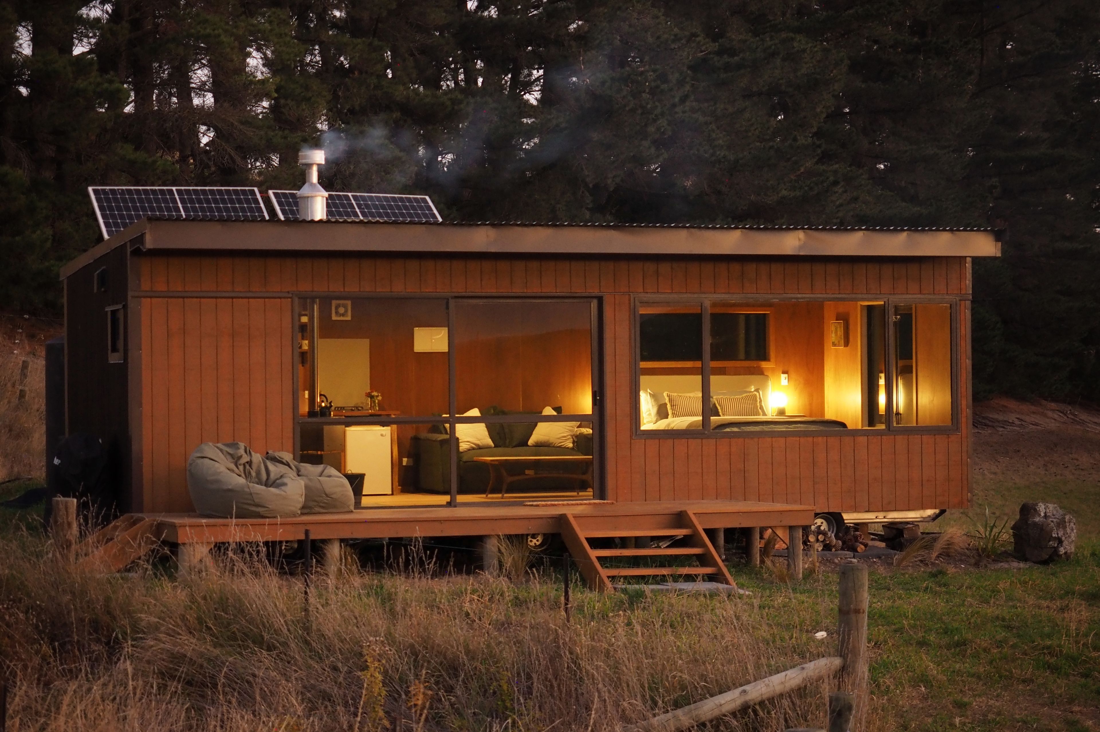 Una cabaña de madera con cama, zona de estar y pequeña cocina.