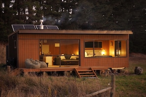 A wooden cabin with a bed, seating area, and a small kitchen.