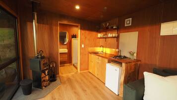 Una cocina compacta con muebles de madera, un lavamanos y un refrigerador pequeño.
