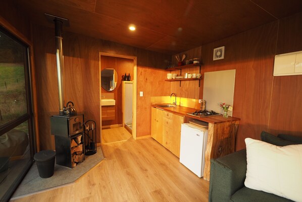 A compact kitchen with wooden cabinets, a sink, and a small refrigerator.
