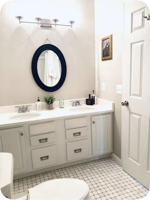 Een badkamer met een wit wastafel, een spiegel, een handdoekrek, een toilet en een deur.