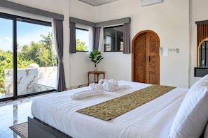 Ein Hotelzimmer mit einem großen Bett, einer Holztür und Blick auf Palmen.