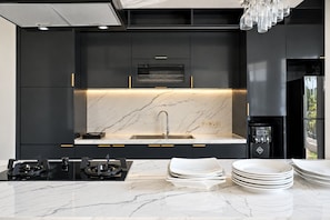 Eine moderne Küche mit schwarzen Schränken, einer Marmor-Spritzschutzwand und einem eingebauten Backofen.