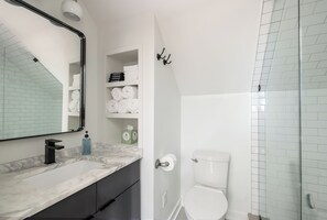 Een moderne badkamer met een marmeren wastafel, toilet en een douchecabine met glazen wanden.