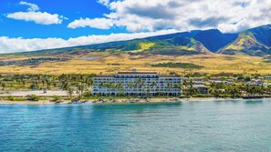 Un hôtel situé sur la côte, avec vue sur la plage, une piscine et un paysage montagneux en arrière-plan.