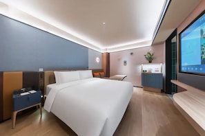 Una habitación de hotel moderna con una cama grande, un escritorio y un televisor.