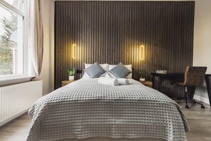 Ein Schlafzimmer mit Bett, Nachttischen, einem Schreibtisch und einem Stuhl.