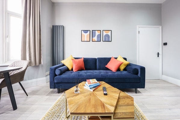 Ein Wohnzimmer mit einem blauen Sofa, einem Couchtisch und einer Tür.