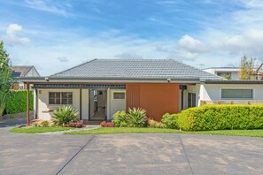 A modern single-story house with a grey tiled roof, a front porch, and a well-maintained garden. - Spacious 4-bedroom house in peaceful Taren Point with AC (Taren Point)
