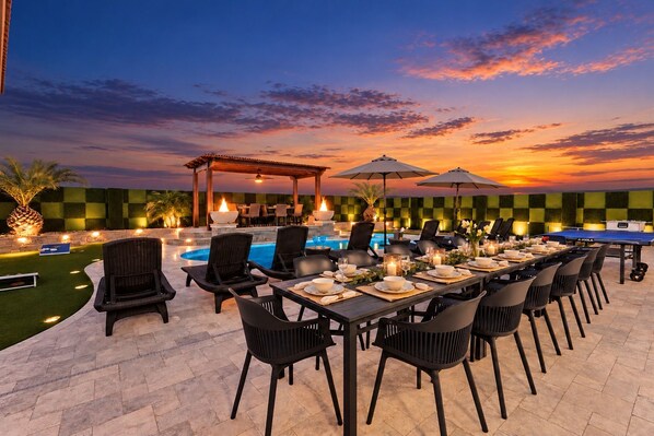 An outdoor dining area with a pool, lounge chairs, and umbrellas.