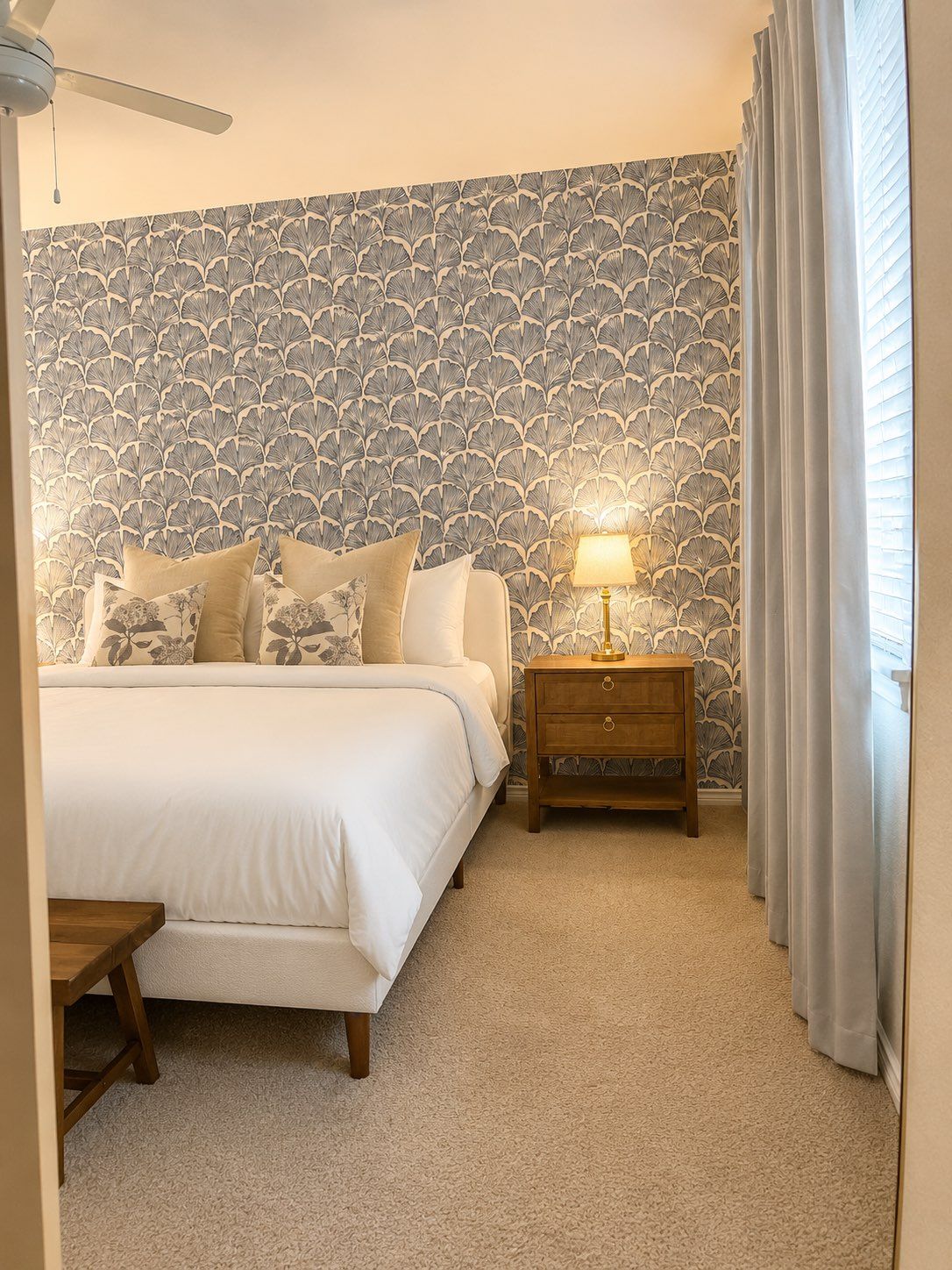 Una camera da letto con un letto, un comodino, una lampada e carta da parati decorata.