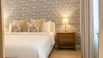Una camera da letto con un letto, un comodino, una lampada e carta da parati decorata.