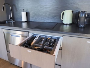 Een moderne keuken met een inbouwvaatwasser, een roestvrijstalen oven en een lade-organizer voor keukengerei.