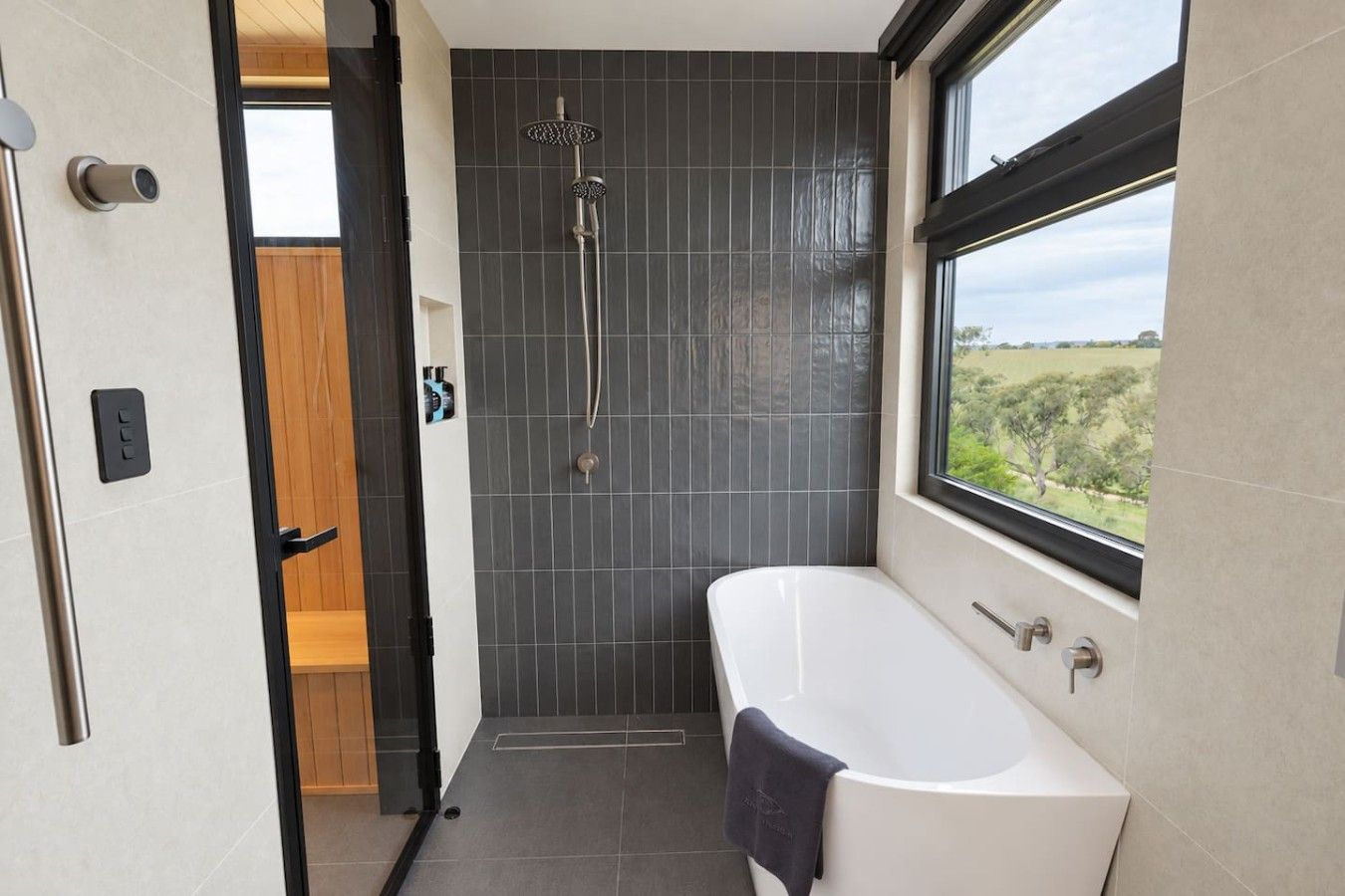 A modern bathroom with a bathtub, shower, and a view through a window.