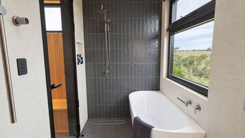 A modern bathroom with a bathtub, shower, and a view through a window.