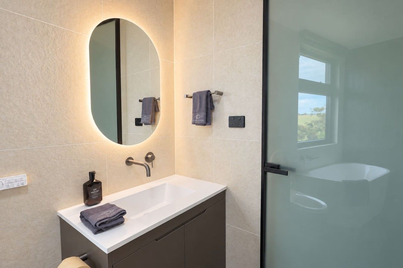 A modern bathroom with a white sink, a large mirror, and a glass shower enclosure.