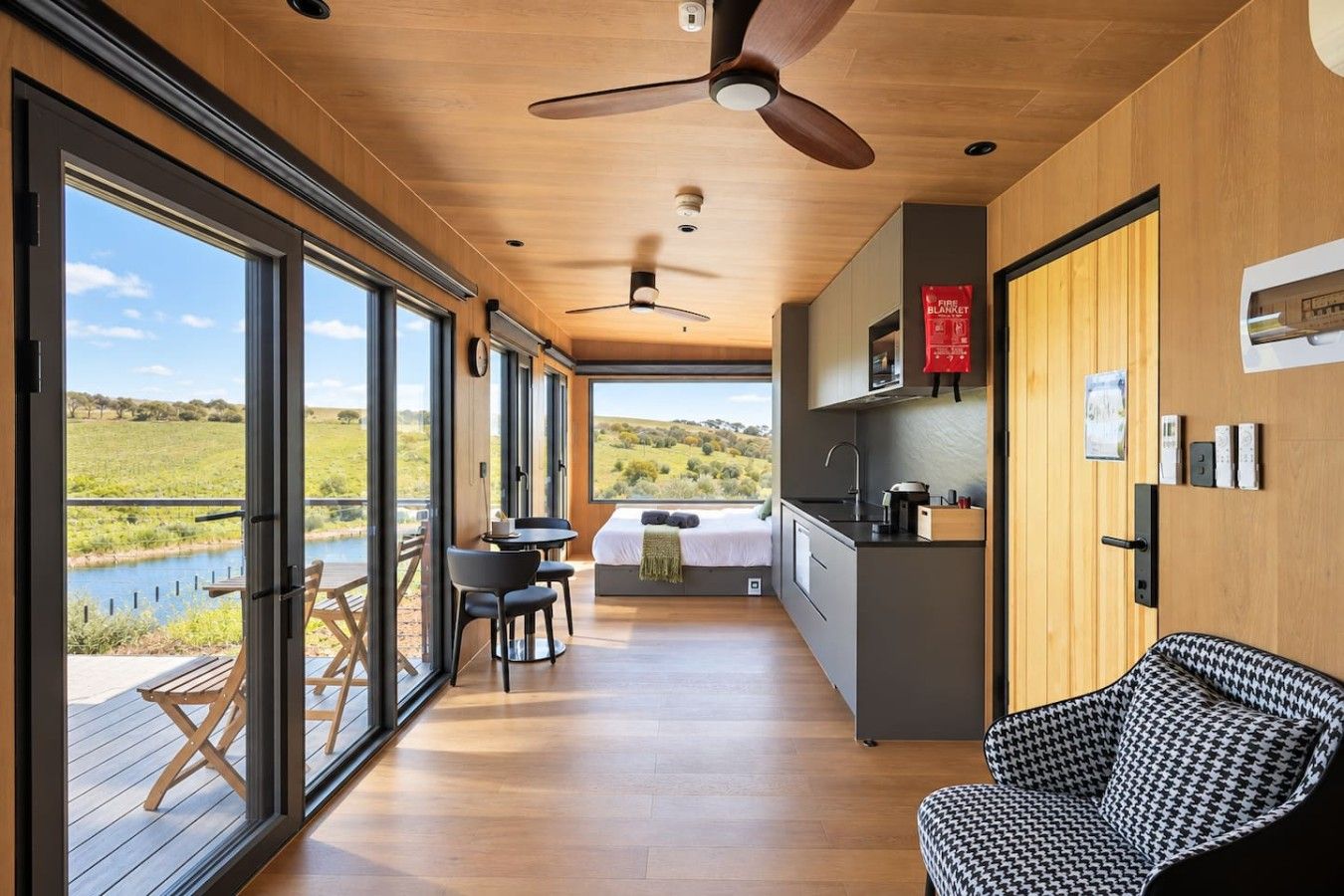 A modern interior with a large window, a ceiling fan, a kitchen area, and a dining space.