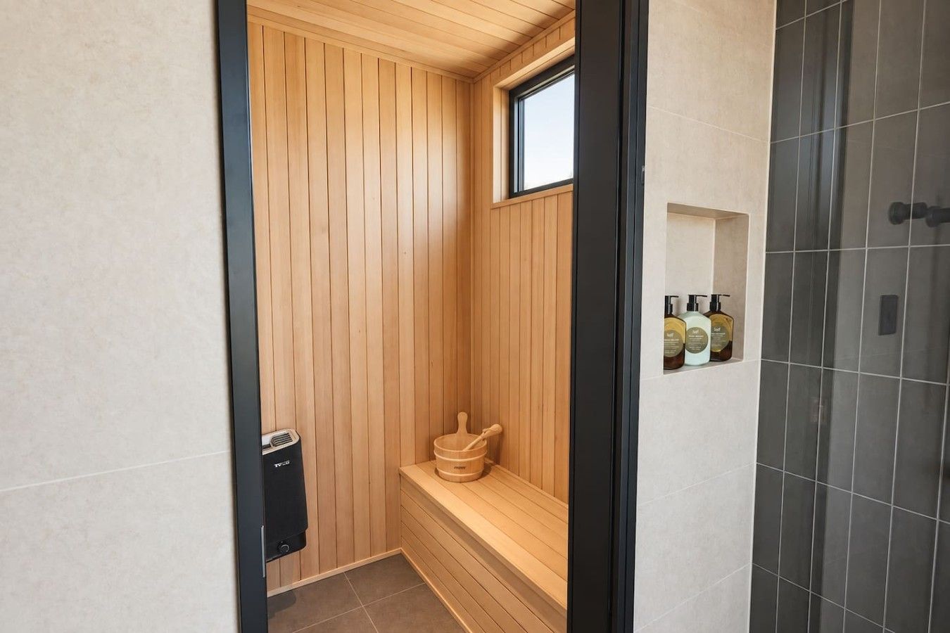 Un sauna avec des murs en bois, un banc et une fenêtre.