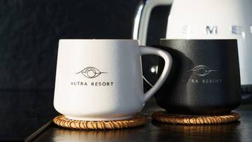 Kaksi kahvimukia, joissa on «AURA RESORT» -logo, tummalla alustalla, jonka päällä on punottu aluslauta.
