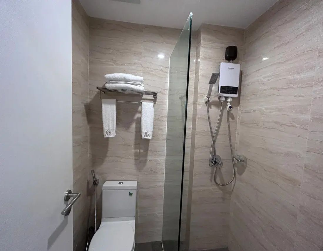 A modern bathroom with a glass-enclosed shower, a toilet, and a towel rack with folded towels.