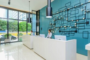 En moderne reception med en receptionist, et stort vindue med udsigt udenomuren og en væg med geometriske mønstre.