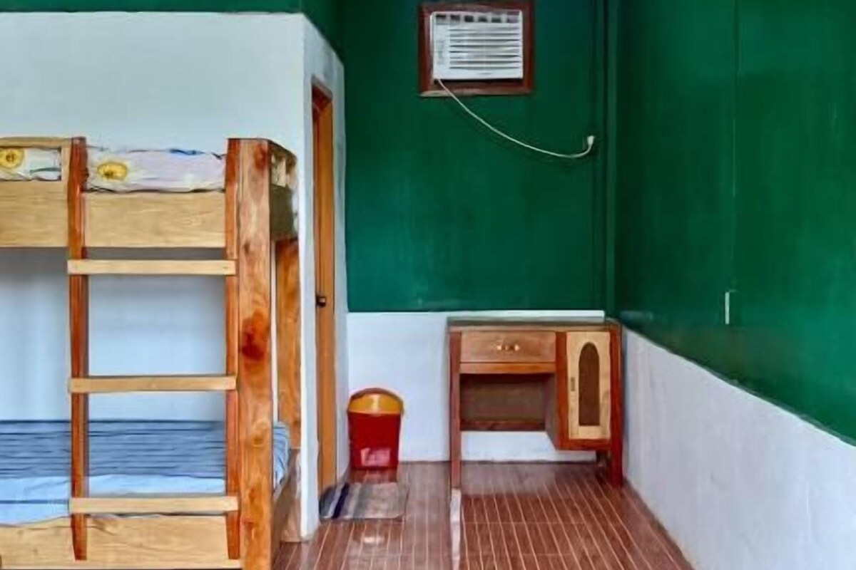 A room with bunk beds, a desk, and a small cabinet.