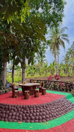 An outdoor seating area with a table and chairs, surrounded by a stone wall and greenery. - Felban's Farm (Carmen, Bohol)