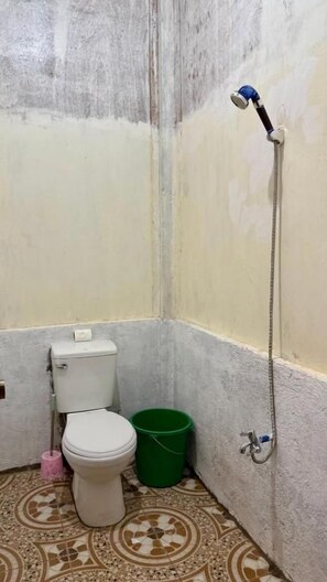 A small bathroom with a toilet, a green bucket, and a shower head. - Felban's Farm (Carmen, Bohol)