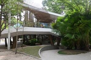 A modern building with a curved roof structure, surrounded by lush greenery and trees. - Alessi's Studio • Coastal Chapter Mactan (Lapu-Lapu)