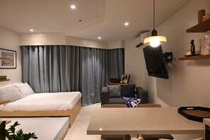 A modern hotel room with a bed, a desk, and a dining table. - Alessi's Studio • Coastal Chapter Mactan (Lapu-Lapu)