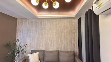 Een moderne woonkamer met een hoekbank, een rond bijzettafeltje en een decoratieve plant.