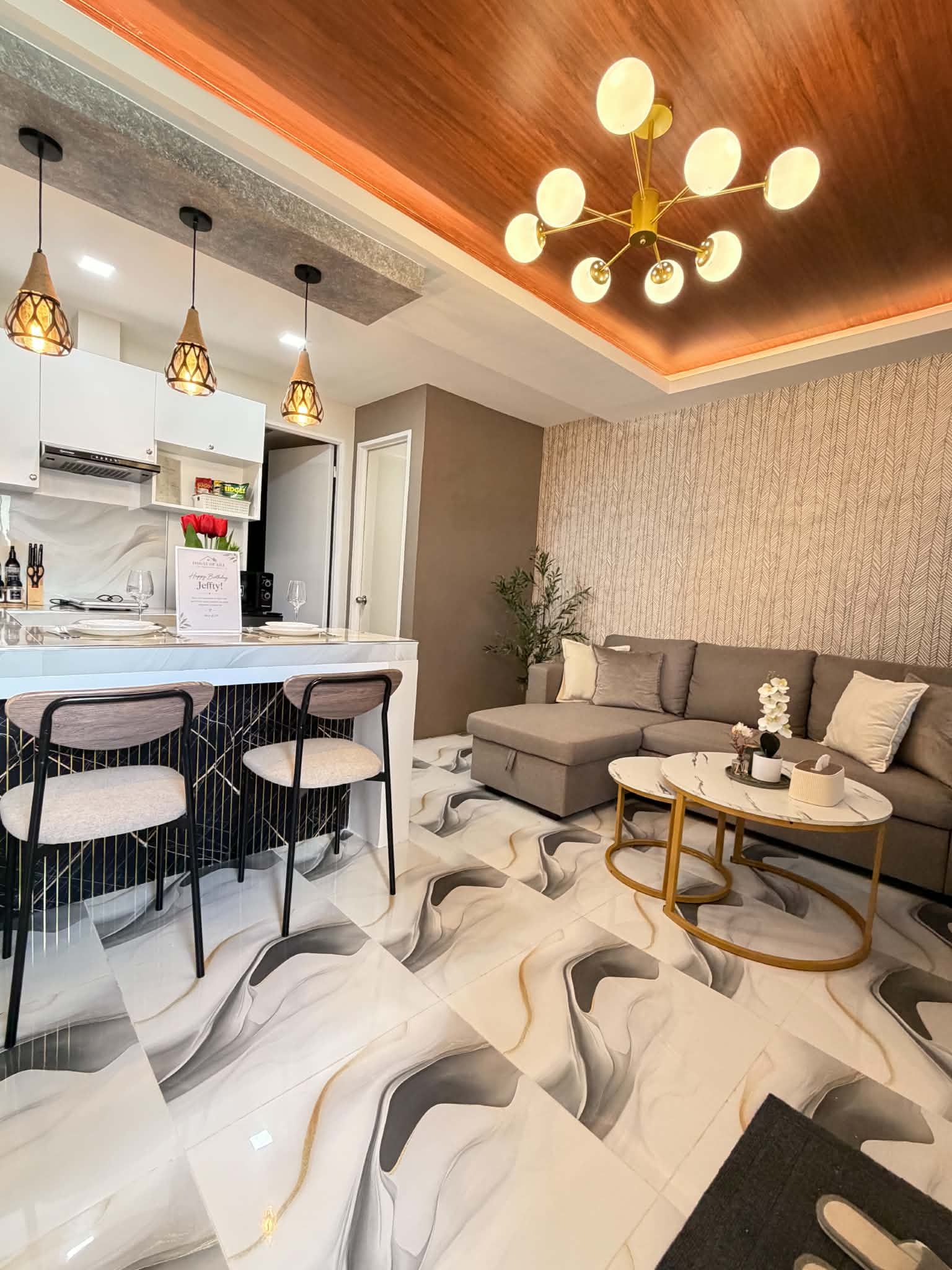 Una sala de estar moderna con un sofá, una mesa de centro y un comedor con taburetes de bar.