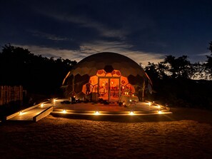 A dome-shaped structure with an open entrance, surrounded by a circular pathway with lights, set in a natural environment. - 6 bed resort Yurt at a luxury Austin Wellness  Ranch 10 minutes from downtown. (Austin)